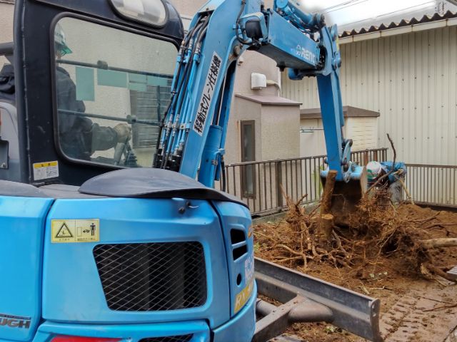 ショベルカーで土の中の根を掘り起こす